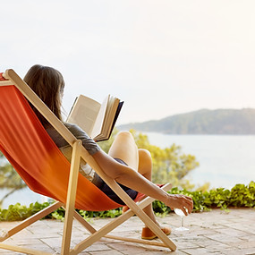 Individual reading by a lake with sunny weather, illustrating a restful lifestyle