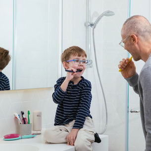 A child and father brush teeth together