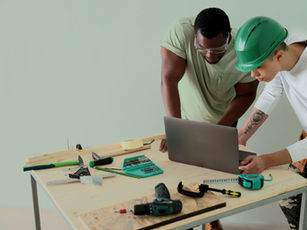 Technicians in hard hats plan maintenance on a laptop at a workbench — what is CMMS