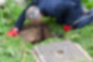 Drain being cleared by worker in navy overalls