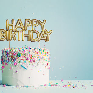 a birthday cake with sprinkles and a sign that reads Happy Birthday