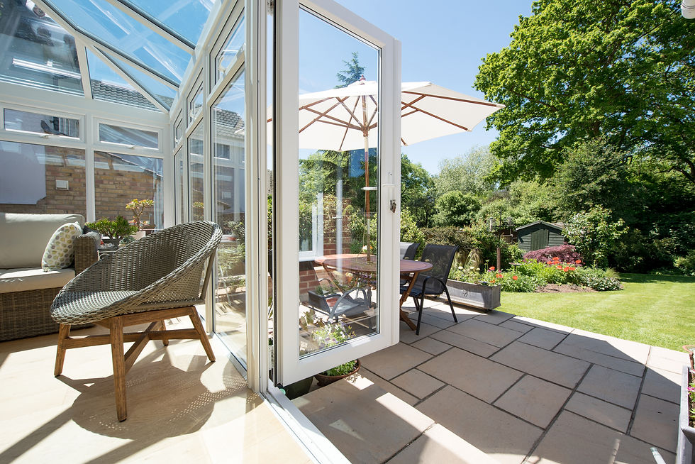 Glass conservatory interior opening onto a green lawn garden
