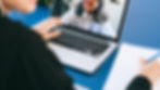 Person im Videogespräch: Ein Mensch nimmt an einem virtuellen Meeting teil, während er Notizen auf einem Blatt Papier macht.