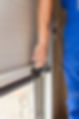 A person in a blue uniform adjusts a garage door mechanism