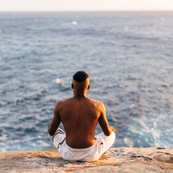personne assise au bord d'une falaise en train de méditer et contempler.