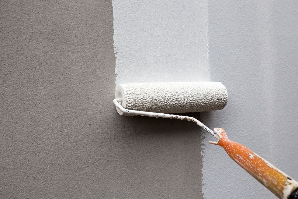 Paint roller applying a smooth coat of white paint on a gray wall