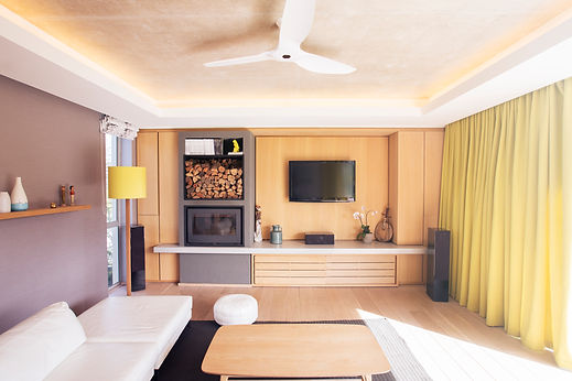 Modern lounge featuring a bespoke wooden feature wall with integrated television, fireplace, and ambient cove lighting