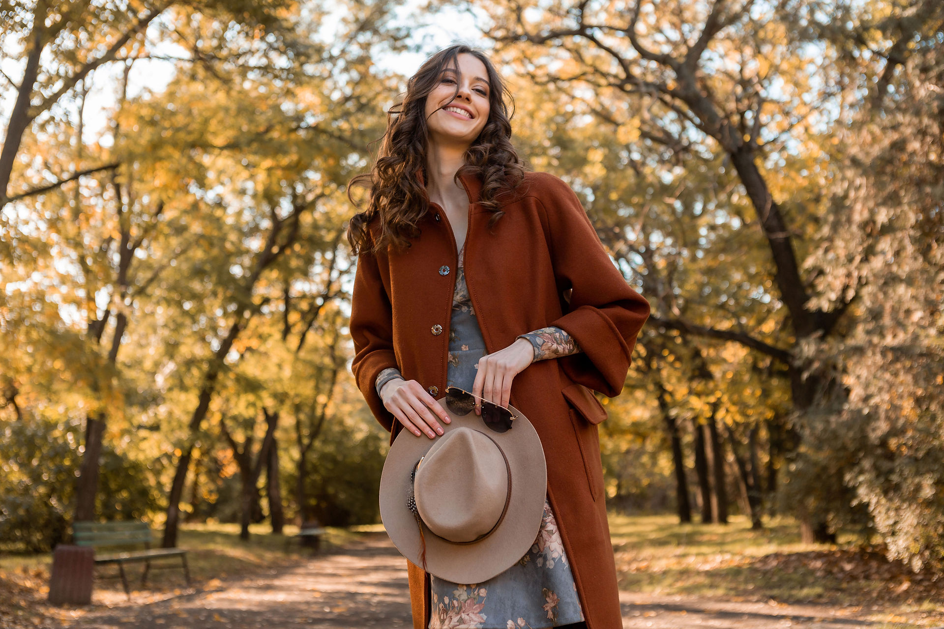 Female wearing long coat and carrying sunglasses and had for an autumn portrait photoshoot