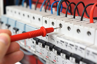 An electrician is checking the electrical switchgear cabinet with a tool