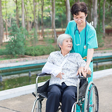 Healthcare worker assisting a seated patient in a clinic.