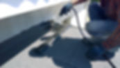 Roofer preparing part of bitumen roofing felt roll for melting by gas heater torch flame