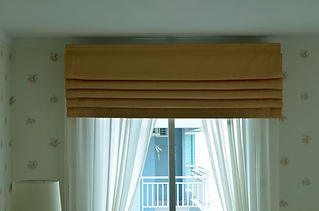 A window with sheer white curtains and a beige, pleated valance