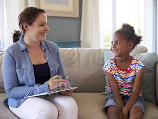 A young girl sitting on a couch with a therapist.