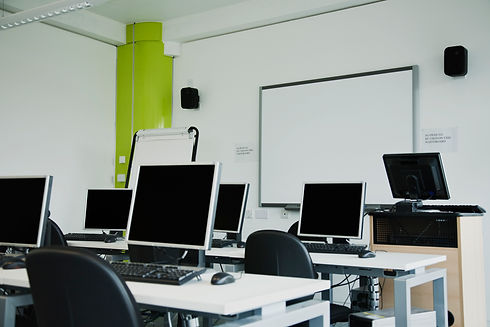 Modern computer classroom with multiple workstations and a whiteboard.