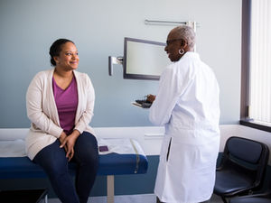 Employee consulting with a doctor in a medical examination room, representing a sick note and its role in workplace absence and disciplinary processes.