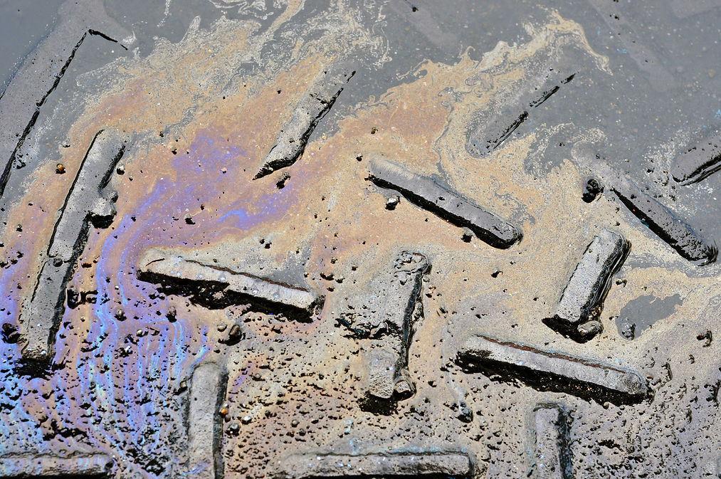 Oil spill on asphalt road background or texture