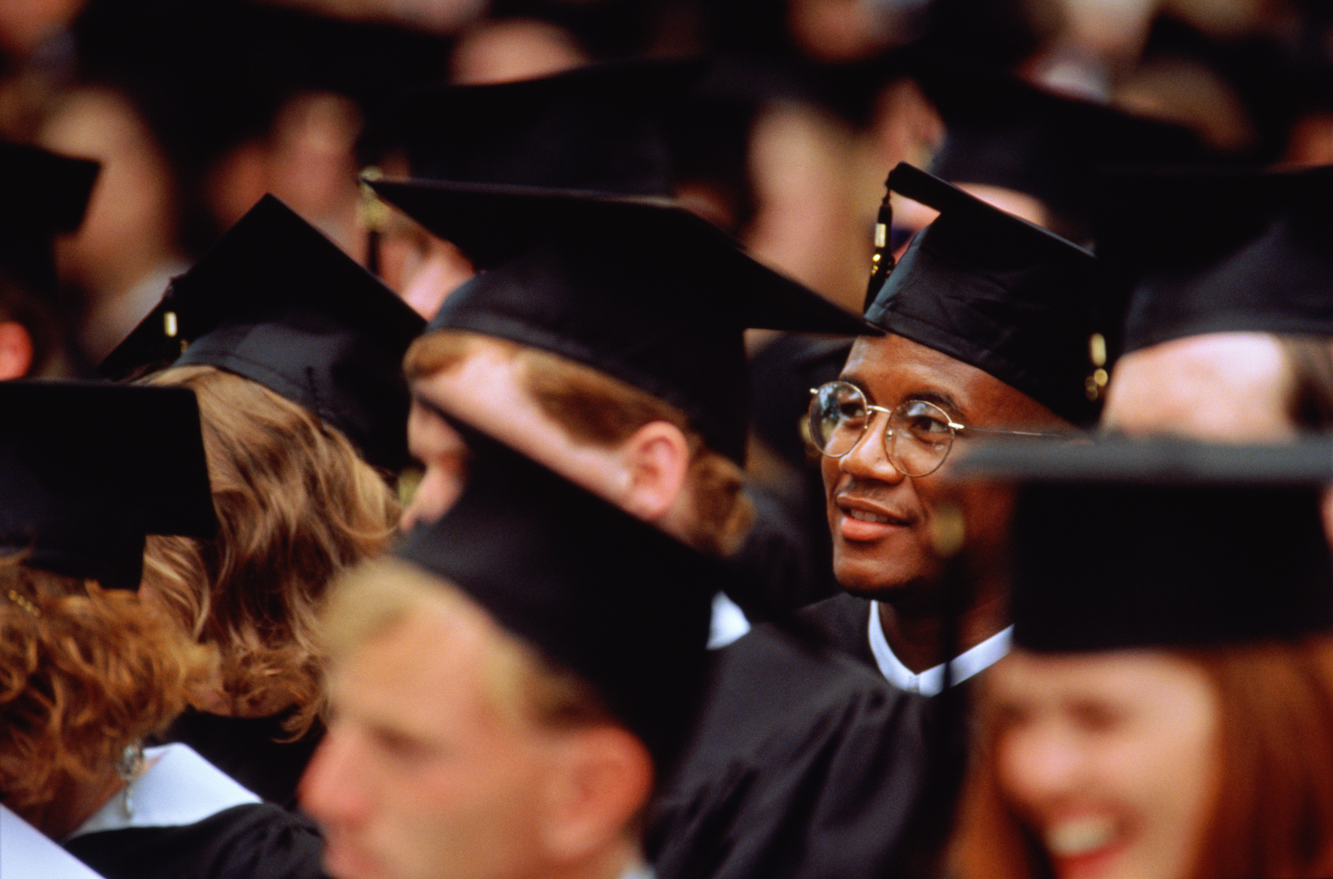 A diverse group of recent college graduates in caps and gowns, smiling and celebrating, symbolizing the culmination of their 
