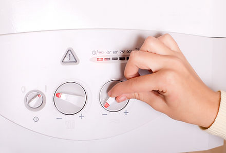 Close up of female hand turning on gas boiler for heating water