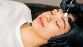 "A woman with her eyes closed receiving a microblading procedure at Shirani Beauty Clinic in Vancouver, as an aesthetician wearing black gloves carefully works on shaping her eyebrows with a precision tool.