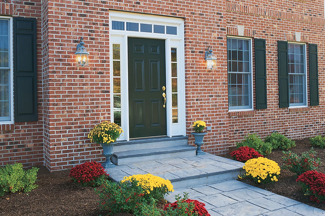 The front door of a house with bricked walls and glass windows