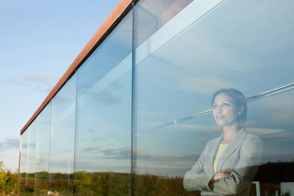 a person looking thoughtfully through a large glass office window