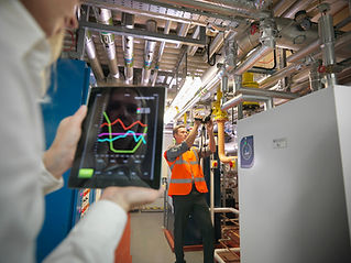 Office workers using digital tablet and camera to check efficiency of office heating in bo