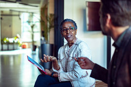 A female executive discussing business strategies with a male colleague in a bright office