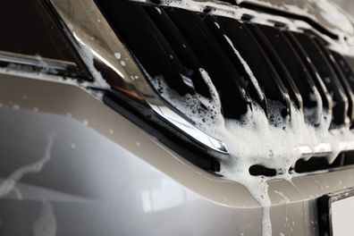 Close-up of a car's front grille covered in white car wash foam