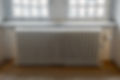A radiator positioned beneath a window in a well-lit room, providing warmth and natural light