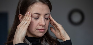 Femme les yeux fermés se tenant les tempes