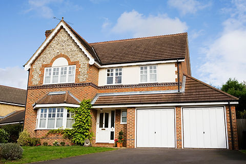 Detached residential house with white double garage doors