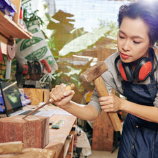 Craftswoman using hammer and chisel in workshop