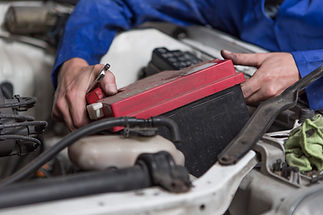 Mechanic repairing car battery under hood