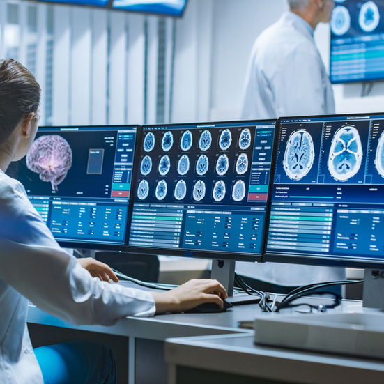 health worker looking at large computer screens utilising AI for health diagnosis