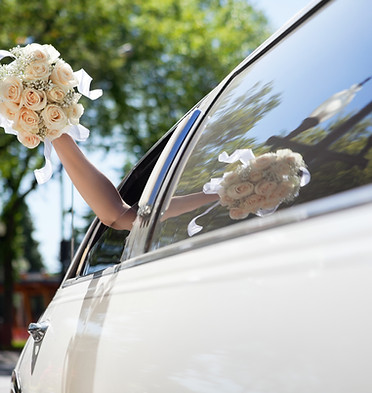Bride Waving Flowers in Limo