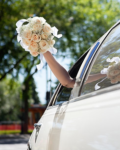 Bride Waving Flowers in Limo