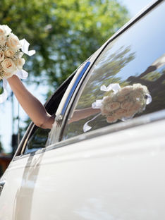 Braut, die Blumen in der Limousine winkt