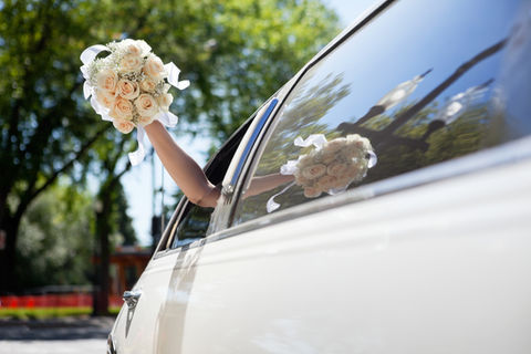 Braut, die Blumen in der Limousine winkt