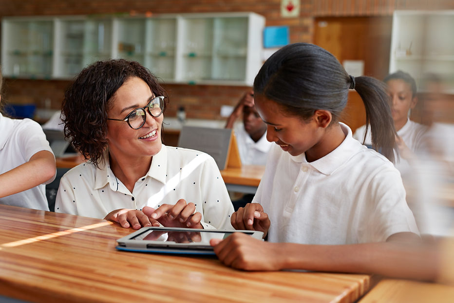A teacher in glasses engages with a young student in a classroom