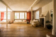 Spacious living room featuring white sofas, wooden floors, and large windows.