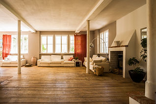 Spacious living room with wooden floors, white sofas, and a modern lamp