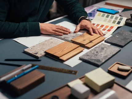 Designer reviewing material samples and color swatches at a workspace, as part of the planning and selection process for an upcoming project.