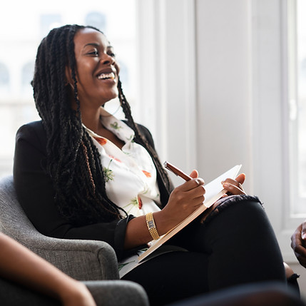 Therapist smiling and taking notes during a virtual therapy session.