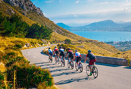 Gruppe von 6 Rennradfahrern bei der Abfahrt zwischen Bergen und See bei schönstem Wetter