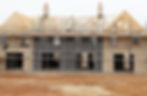 A row of houses under construction with scaffolding and wooden roof framework
