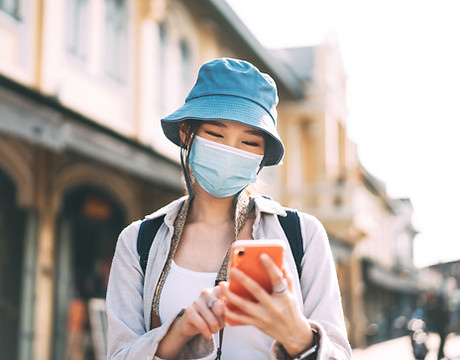 Person in Mask Looking At Smartphone