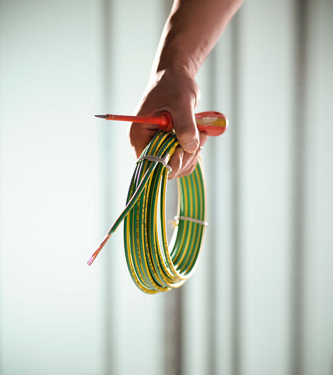 Man holding roll of electrical cable and screwdriver