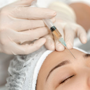 Person receiving a botox injection in the forehead by gloved hands. Close-up, serene setting, white cap on head.