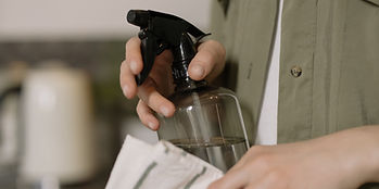 A woman holding a spray bottle and cleaning cloth, ready to clean.