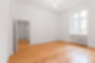 Close-up of a man installing light hardwood floor panels with a hammer and tape measure